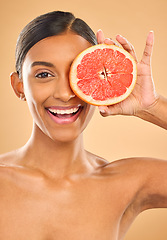 Image showing Face smile, skincare and woman with grapefruit in studio isolated on a brown background. Portrait, natural cosmetics and happy Indian female model with citrus fruit for vitamin c, nutrition or beauty