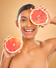 Image showing Face smile, skincare and woman with grapefruit in studio isolated on a brown background. Portrait, natural cosmetics and happy Indian female model with citrus fruit for vitamin c, nutrition or beauty