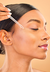 Image showing Skincare, face and woman with serum in studio isolated on a brown background. Dermatology, cosmetics and Indian female model with hyaluronic acid, retinol or essential oil product for healthy skin.