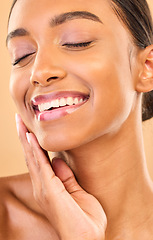 Image showing Beauty, face and smile of woman with makeup in studio for skincare, cosmetics and dermatology. Aesthetic female .hand for self care, natural skin and spa facial shine results on a brown background