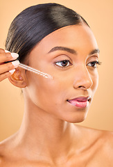 Image showing Skincare, face and woman with serum in studio isolated on a brown background. Dermatology, cosmetics and Indian female model with hyaluronic acid, retinol or essential oil product for healthy skin.