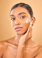 Image showing Face portrait, skincare and woman with cream in studio isolated on a brown background. Dermatology, cosmetics or confident Indian female model with lotion, beauty creme or moisturizer for skin health