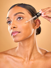 Image showing Face, skincare serum and woman in studio isolated on a brown background. Dermatology cosmetics, thinking and Indian female model with hyaluronic acid, beauty retinol or essential oil for healthy skin