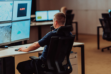 Image showing Group of Security data center operators working in a CCTV monitoring room looking on multiple monitors.Officers Monitoring Multiple Screens for Suspicious Activities