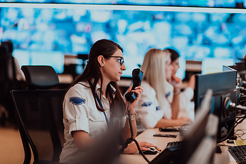 Image showing Group of Security data center operators working in a CCTV monitoring room looking on multiple monitors.Officers Monitoring Multiple Screens for Suspicious Activities