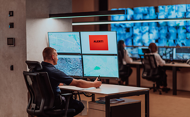 Image showing Group of Security data center operators working in a CCTV monitoring room looking on multiple monitors.Officers Monitoring Multiple Screens for Suspicious Activities