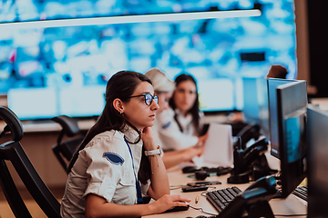 Image showing Group of Security data center operators working in a CCTV monitoring room looking on multiple monitors.Officers Monitoring Multiple Screens for Suspicious Activities