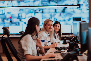 Image showing Group of Security data center operators working in a CCTV monitoring room looking on multiple monitors.Officers Monitoring Multiple Screens for Suspicious Activities