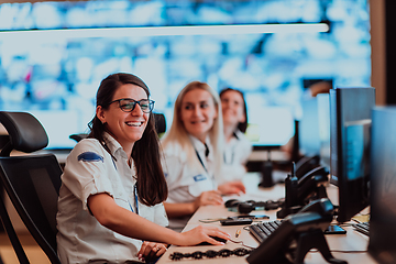 Image showing Group of Security data center operators working in a CCTV monitoring room looking on multiple monitors.Officers Monitoring Multiple Screens for Suspicious Activities