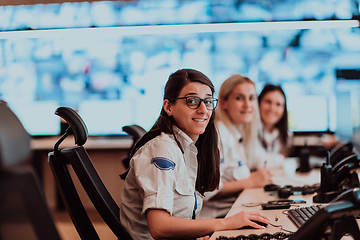 Image showing Group of Security data center operators working in a CCTV monitoring room looking on multiple monitors.Officers Monitoring Multiple Screens for Suspicious Activities