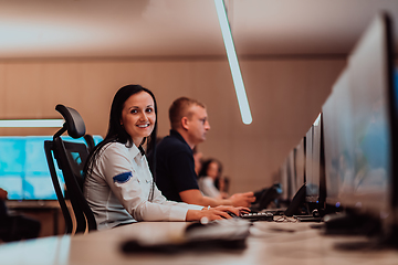 Image showing Group of Security data center operators working in a CCTV monitoring room looking on multiple monitors.Officers Monitoring Multiple Screens for Suspicious Activities