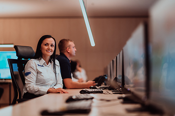 Image showing Group of Security data center operators working in a CCTV monitoring room looking on multiple monitors.Officers Monitoring Multiple Screens for Suspicious Activities