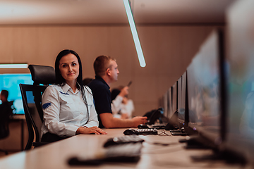 Image showing Group of Security data center operators working in a CCTV monitoring room looking on multiple monitors.Officers Monitoring Multiple Screens for Suspicious Activities