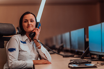 Image showing Female security operator working in a data system control room offices Technical Operator Working at workstation with multiple displays, security guard working on multiple monitors