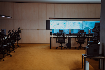 Image showing Empty interior of big modern security system control room, workstation with multiple displays, monitoring room with at security data center Empty office, desk, and chairs at a main CCTV security data