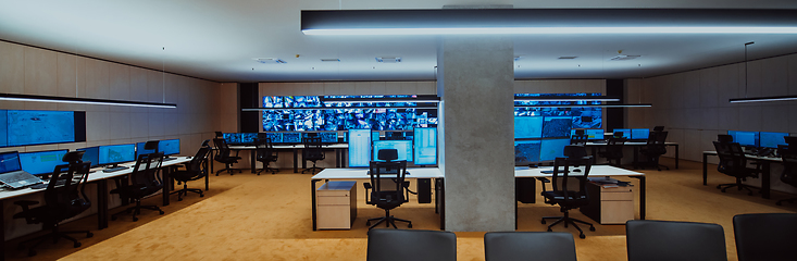 Image showing Empty interior of big modern security system control room, workstation with multiple displays, monitoring room with at security data center Empty office, desk, and chairs at a main CCTV security data