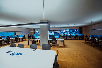 Image showing Empty interior of big modern security system control room, workstation with multiple displays, monitoring room with at security data center Empty office, desk, and chairs at a main CCTV security data