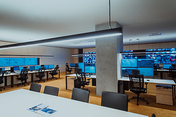 Image showing Empty interior of big modern security system control room, workstation with multiple displays, monitoring room with at security data center Empty office, desk, and chairs at a main CCTV security data