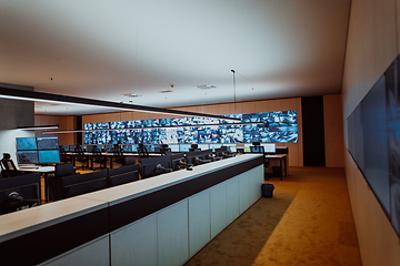 Image showing Group of Security data center operators working in a CCTV monitoring room looking on multiple monitors.Officers Monitoring Multiple Screens for Suspicious Activities