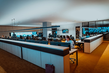 Image showing Group of Security data center operators working in a CCTV monitoring room looking on multiple monitors.Officers Monitoring Multiple Screens for Suspicious Activities