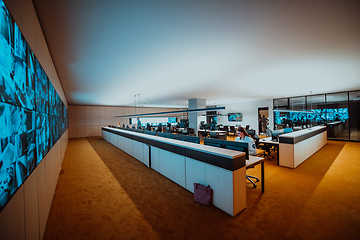 Image showing Group of Security data center operators working in a CCTV monitoring room looking on multiple monitors.Officers Monitoring Multiple Screens for Suspicious Activities