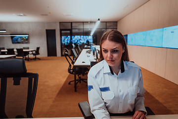 Image showing Female security operator working in a data system control room offices Technical Operator Working at workstation with multiple displays, security guard working on multiple monitors