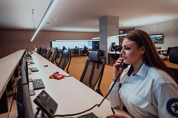 Image showing Female security operator working in a data system control room offices Technical Operator Working at workstation with multiple displays, security guard working on multiple monitors