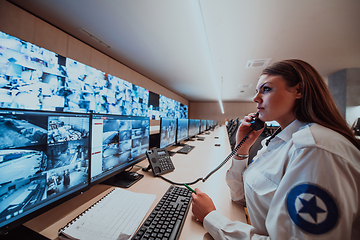 Image showing Female security operator working in a data system control room offices Technical Operator Working at workstation with multiple displays, security guard working on multiple monitors