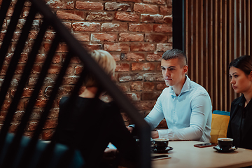 Image showing Happy businesspeople smiling cheerfully during a meeting in a coffee shop. Group of successful business professionals working as a team in a multicultural workplace.