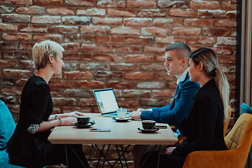 Image showing Happy businesspeople smiling cheerfully during a meeting in a coffee shop. Group of successful business professionals working as a team in a multicultural workplace.