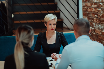 Image showing Happy businesspeople smiling cheerfully during a meeting in a coffee shop. Group of successful business professionals working as a team in a multicultural workplace.