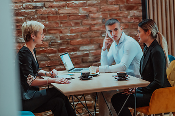 Image showing Happy businesspeople smiling cheerfully during a meeting in a coffee shop. Group of successful business professionals working as a team in a multicultural workplace.