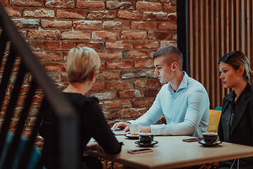 Image showing Happy businesspeople smiling cheerfully during a meeting in a coffee shop. Group of successful business professionals working as a team in a multicultural workplace.