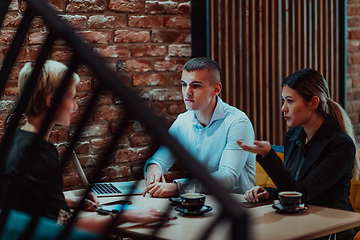 Image showing Happy businesspeople smiling cheerfully during a meeting in a coffee shop. Group of successful business professionals working as a team in a multicultural workplace.