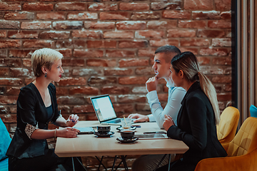 Image showing Happy businesspeople smiling cheerfully during a meeting in a coffee shop. Group of successful business professionals working as a team in a multicultural workplace.