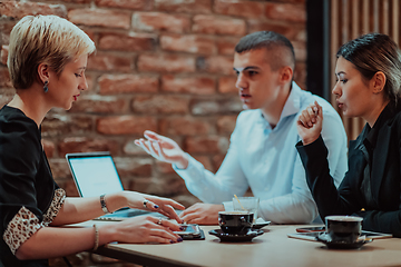 Image showing Happy businesspeople smiling cheerfully during a meeting in a coffee shop. Group of successful business professionals working as a team in a multicultural workplace.