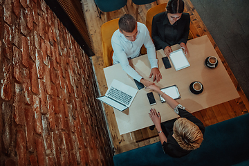 Image showing Top view photo of business shaking hands, finishing up meeting. Successful businesspeople handshaking after good deal