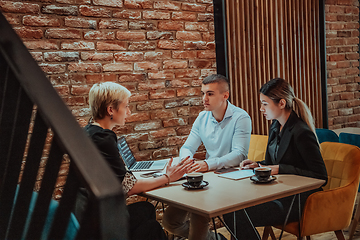 Image showing Happy businesspeople smiling cheerfully during a meeting in a coffee shop. Group of successful business professionals working as a team in a multicultural workplace.