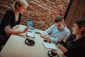 Image showing Happy businesspeople smiling cheerfully during a meeting in a coffee shop. Group of successful business professionals working as a team in a multicultural workplace.