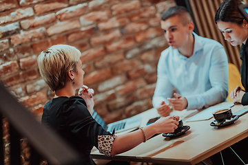 Image showing Happy businesspeople smiling cheerfully during a meeting in a coffee shop. Group of successful business professionals working as a team in a multicultural workplace.