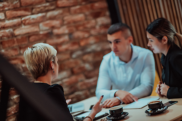 Image showing Happy businesspeople smiling cheerfully during a meeting in a coffee shop. Group of successful business professionals working as a team in a multicultural workplace.