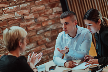 Image showing Happy businesspeople smiling cheerfully during a meeting in a coffee shop. Group of successful business professionals working as a team in a multicultural workplace.