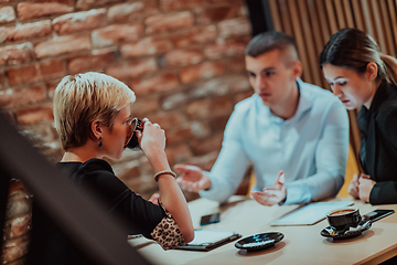 Image showing Happy businesspeople smiling cheerfully during a meeting in a coffee shop. Group of successful business professionals working as a team in a multicultural workplace.