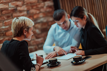 Image showing Happy businesspeople smiling cheerfully during a meeting in a coffee shop. Group of successful business professionals working as a team in a multicultural workplace.