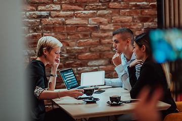 Image showing Happy businesspeople smiling cheerfully during a meeting in a coffee shop. Group of successful business professionals working as a team in a multicultural workplace.