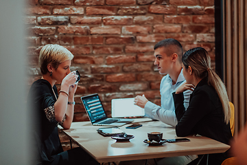 Image showing Happy businesspeople smiling cheerfully during a meeting in a coffee shop. Group of successful business professionals working as a team in a multicultural workplace.