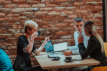 Image showing Happy businesspeople smiling cheerfully during a meeting in a coffee shop. Group of successful business professionals working as a team in a multicultural workplace.