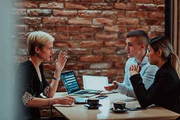 Image showing Happy businesspeople smiling cheerfully during a meeting in a coffee shop. Group of successful business professionals working as a team in a multicultural workplace.