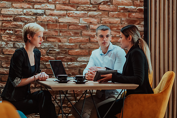 Image showing Happy businesspeople smiling cheerfully during a meeting in a coffee shop. Group of successful business professionals working as a team in a multicultural workplace.