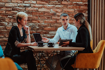 Image showing Happy businesspeople smiling cheerfully during a meeting in a coffee shop. Group of successful business professionals working as a team in a multicultural workplace.